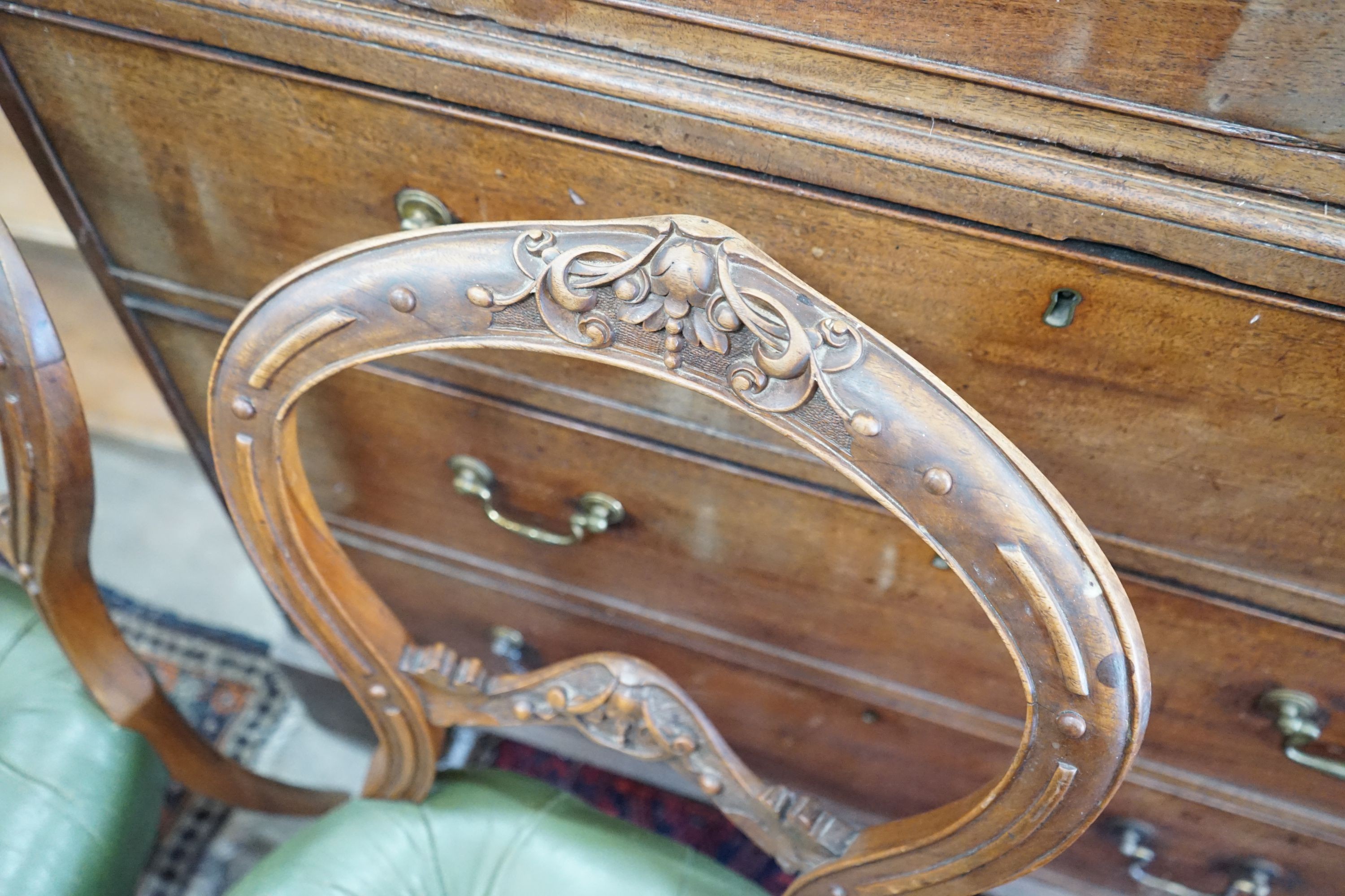 A set of six Victorian carved walnut and buttoned green leather spoon back dining chairs